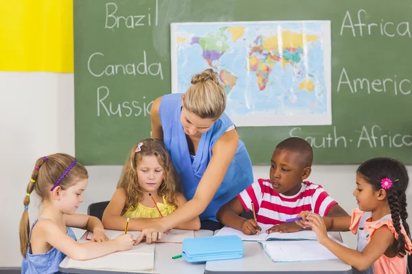 Teacher helping kids with their homework in classroom — Stock Photo, Image