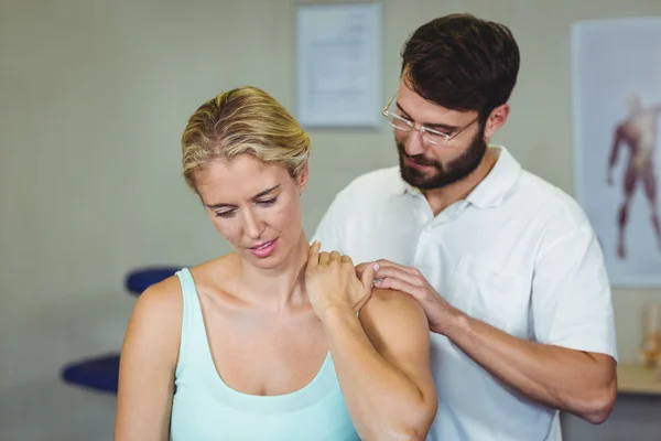 Мужской физиотерапевт делает массаж шеи пациентке — стоковое фото