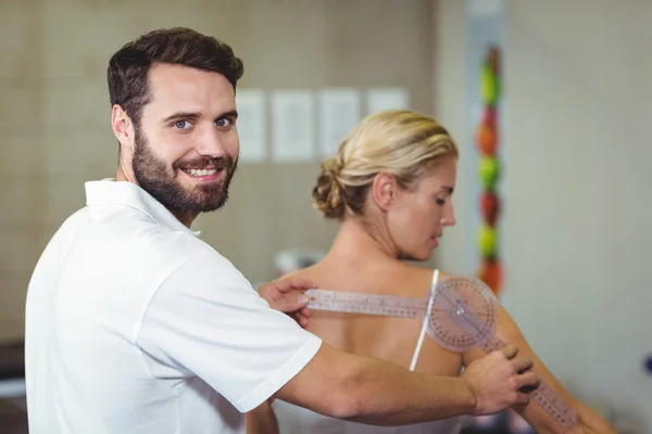 Terapeuta masculino que mide la espalda del paciente femenino con goniómetro —  Fotos de Stock
