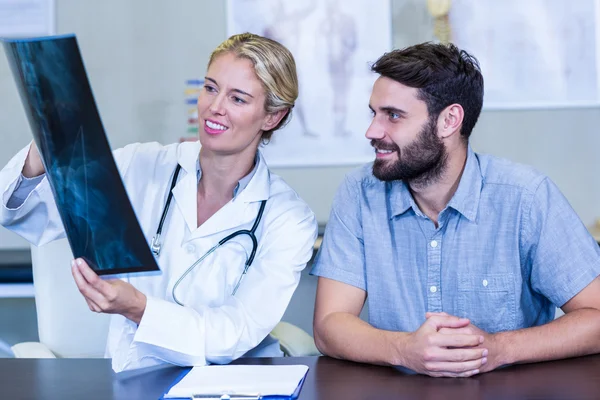 Physiotherapeut zeigt Röntgenbild einer Patientin — Stockfoto