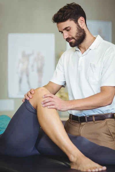 Fisioterapeuta masculino dando masaje de rodilla a paciente femenino — Foto de Stock