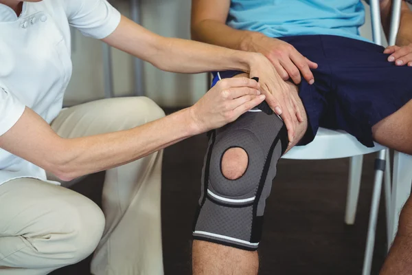 Fysiotherapeut onderzoekende patiënten knie — Stockfoto