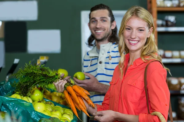 Happy couple selecting fruits and carrots — Stock Photo, Image