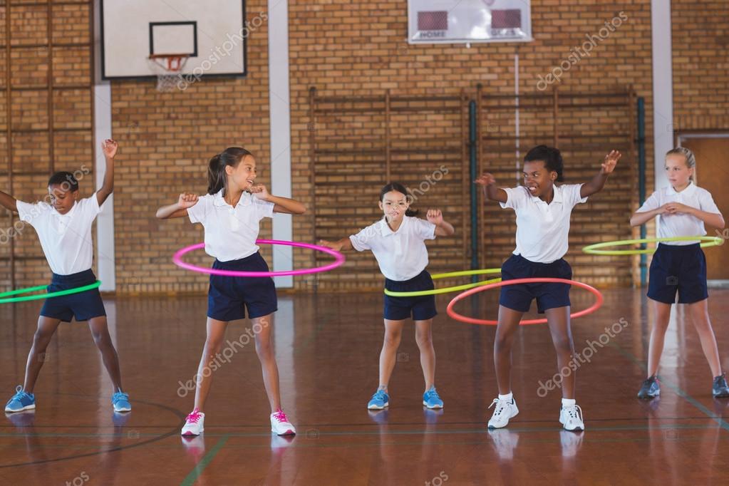 Anak-anak sekolah bermain dengan hula hoop di lapangan basket
