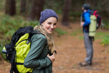 Woman looking back while hiking in forest clipart