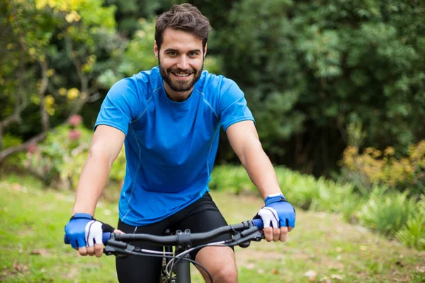 Male athletic standing with mountain bike in forest — Stock Photo, Image