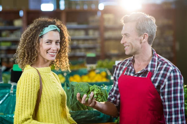 Personal masculino sonriente ayudando a una mujer con compras de comestibles — Foto de Stock