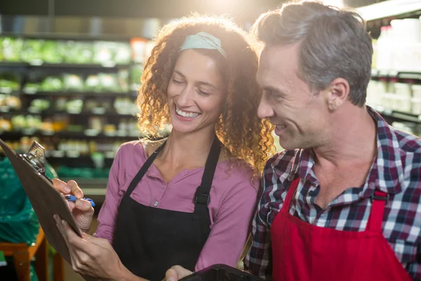 Staffs writing on clipboard in organic section — Stock Photo, Image