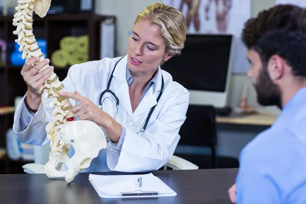 Fisioterapeuta explicando modelo de columna vertebral al paciente — Foto de Stock