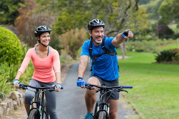 Casal atlético apontando enquanto andava de bicicleta — Fotografia de Stock