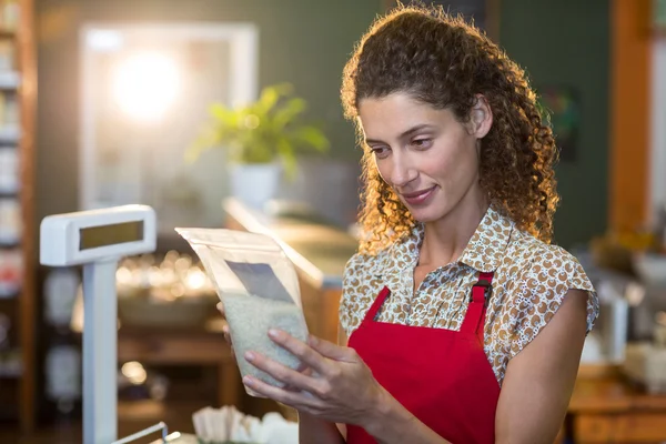 Vrouwelijk personeel kijken naar een item van de kruidenier op betaling teller — Stockfoto