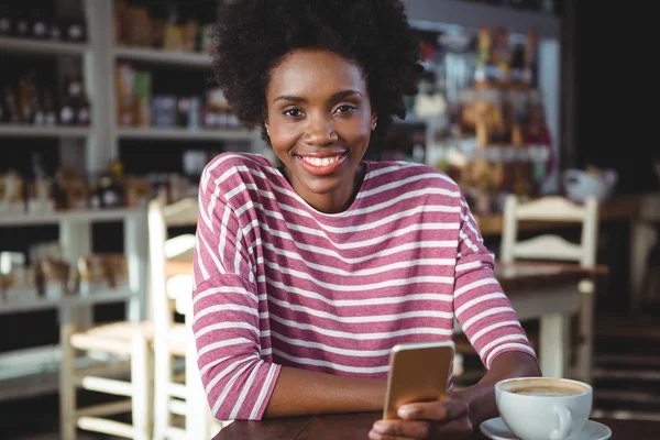 Mujer sonriente usando el teléfono móvil en la cafetería — Foto de Stock