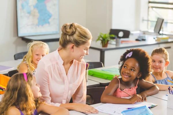 Lärare att hjälpa barnen med deras läxor i klassrummet — Stockfoto