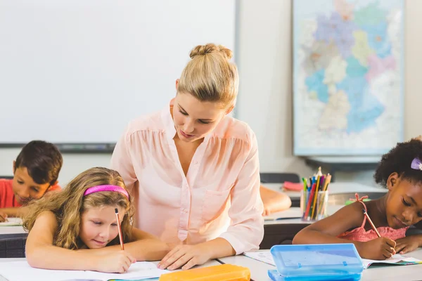 Lärare att hjälpa barnen med deras läxor i klassrummet — Stockfoto