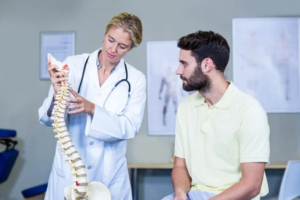 Physiotherapist explaining the spine model to patient — Stock Photo, Image