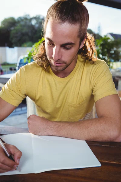 Junger Mann schreibt in Notizbuch — Stockfoto