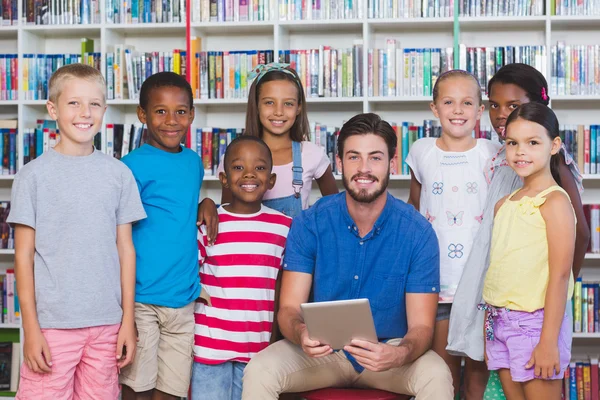 Leraar lesgeven kinderen op digitale tablet in bibliotheek — Stockfoto