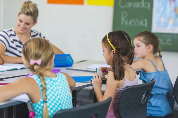 Lärare att hjälpa barnen med deras läxor i klassrummet — Stockfoto