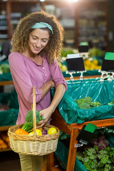 Mulher sorridente comprando legumes na seção orgânica — Fotografia de Stock