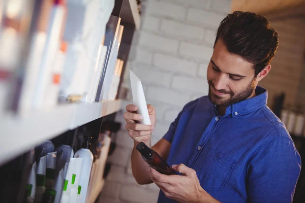 Male hair dresser selecting shampoo from shelf — Stock Photo, Image