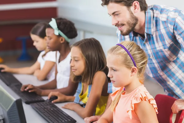 Lärare hjälpa skolflickor lära datorn — Stockfoto