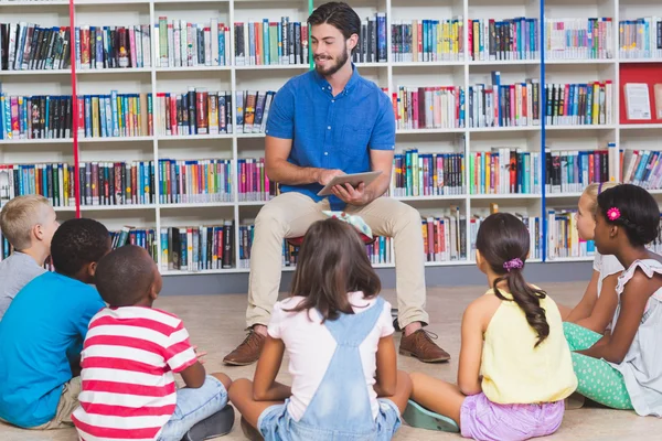 Leraar lesgeven kinderen op digitale tablet in bibliotheek — Stockfoto