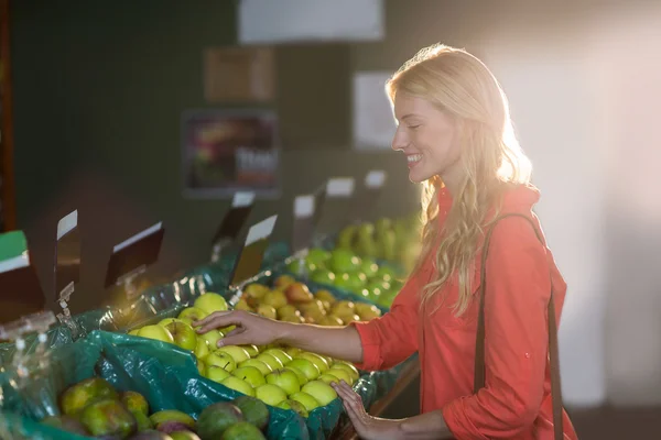 Sorrindo mulher selecionando maçãs verdes — Fotografia de Stock