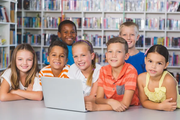 Portrait of school kids using laptop in library — Stock Photo, Image