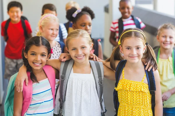 Smiling kids standing with arm around in corridor — Stock Photo, Image