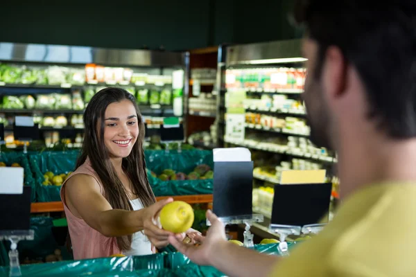Mujer dando fruta al cajero para la facturación —  Fotos de Stock