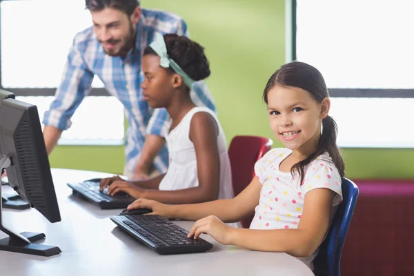 Schoolgirl using computer in classroom — Stock Photo, Image