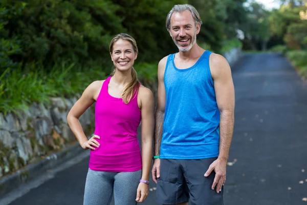 Athletic couple standing on road after jogging — Stock Photo, Image