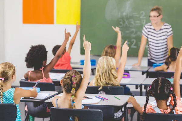School kids verhogen hand in klaslokaal — Stockfoto