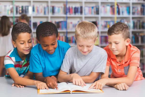 Crianças da escola lendo livro juntos na biblioteca — Fotografia de Stock