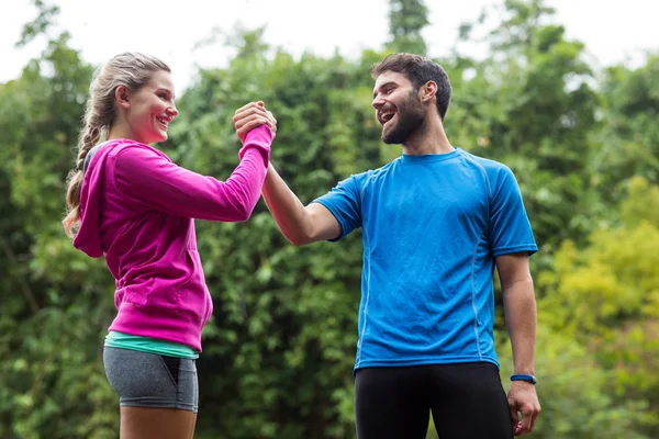 Athletic par hålla händerna i skogen — Stockfoto