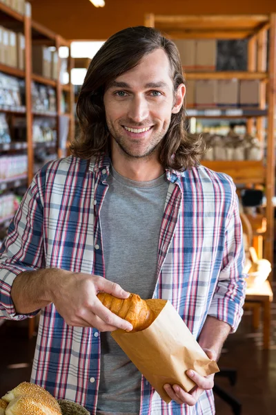 Muž v papírovém sáčku uvedení croissant — Stock fotografie