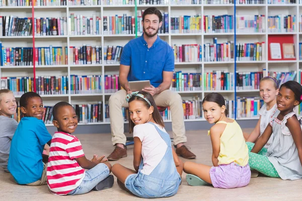 Leraar lesgeven kinderen op digitale tablet in bibliotheek — Stockfoto