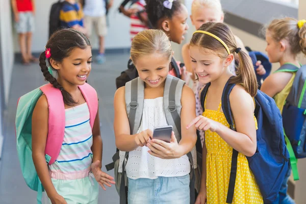 Crianças da escola usando telefone celular no corredor — Fotografia de Stock