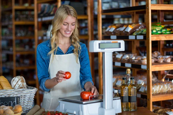 Female staff weighting vegetables on scale — Stock Photo, Image