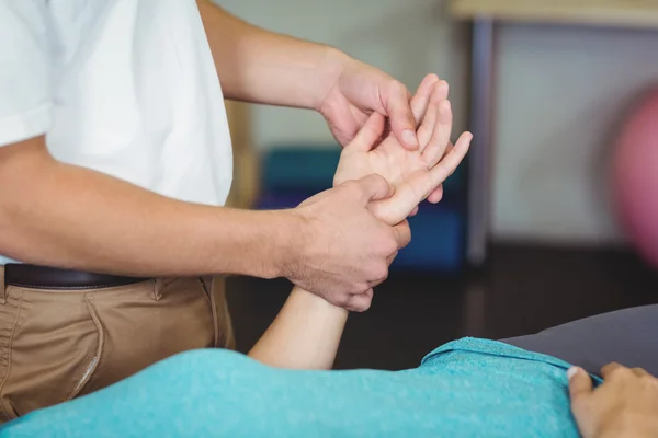 Male physiotherapist giving hand massage to female patient in clinic 