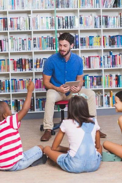 Leraar lesgeven kinderen op digitale tablet in bibliotheek — Stockfoto