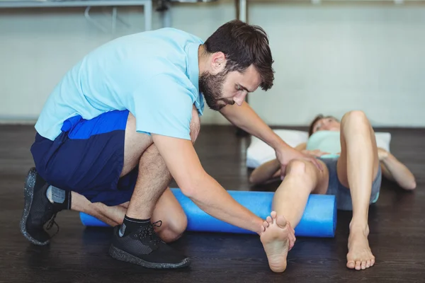 Physiotherapist doing leg therapy to a woman using foam roll — Stock Photo, Image