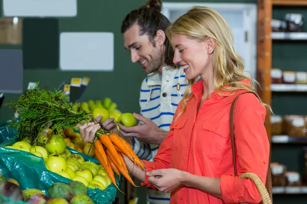 Casal feliz selecionando frutas e cenouras — Fotografia de Stock