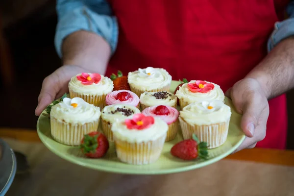 Personal que sostiene una bandeja de cupcakes — Foto de Stock