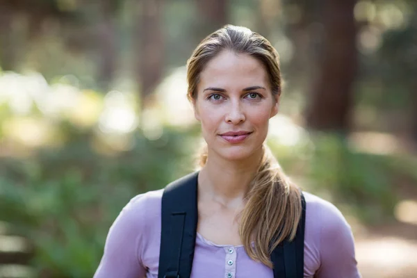 Selbstbewusste Frau steht mit Rucksack im Wald — Stockfoto