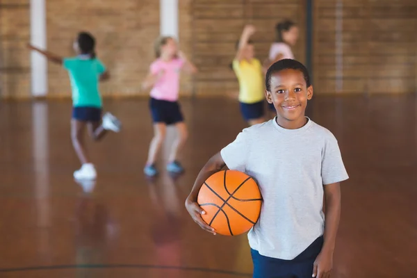 Menino de pé com bola na quadra de basquete — Fotografia de Stock