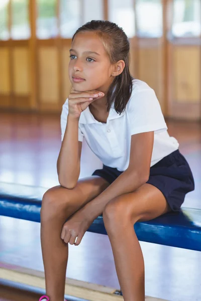 Thoughtful schoolgirl sitting in basketball court — Stock Photo, Image