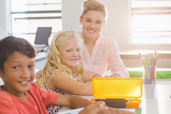 Lärare att hjälpa barnen med deras läxor i klassrummet — Stockfoto