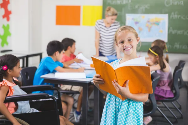 Skolflicka håller en bok i klassrummet — Stockfoto