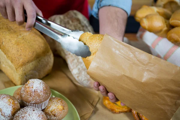 Mitarbeiter packen Brot in Papiertüte — Stockfoto